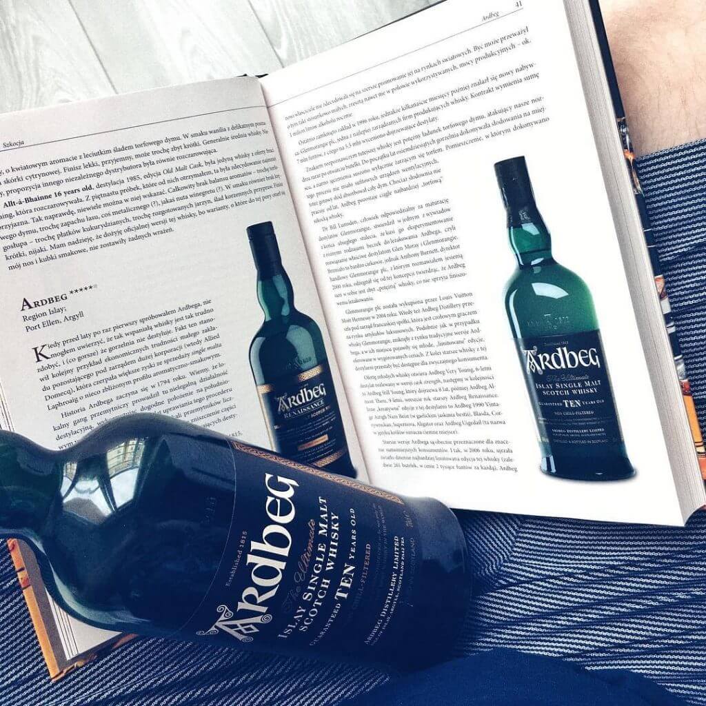Butelka 10 letniej whisky Ardbeg na tle książki o temacie whisky